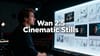 Director in a dark studio facing a glowing wall of cinematic storyboards, with bold central title text reading “Wan 2.5 Cinematic Stills” over the scene.